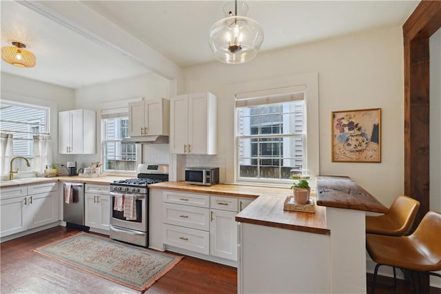 kitchen with dark wood-type flooring, butcher block countertops, a breakfast bar, tasteful backsplash, and stainless steel appliances