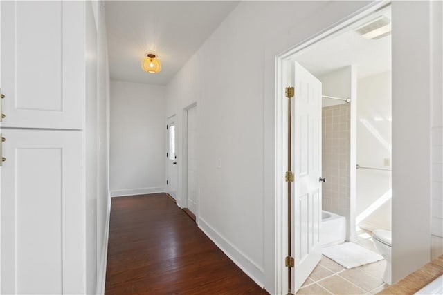 corridor featuring visible vents, baseboards, and wood finished floors