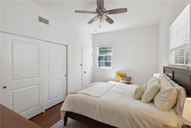 bedroom featuring visible vents, a ceiling fan, a closet, and dark wood-style flooring