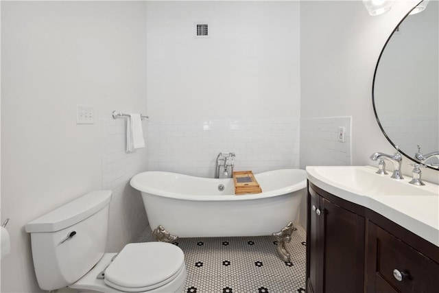 full bath with vanity, visible vents, a soaking tub, tile walls, and toilet