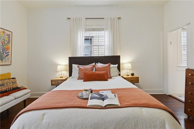 bedroom with multiple windows, dark wood-type flooring, and baseboards