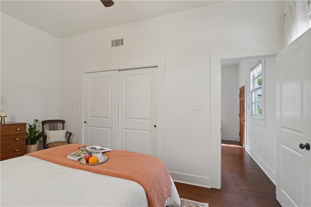 bedroom with visible vents, baseboards, a closet, and dark wood-style floors