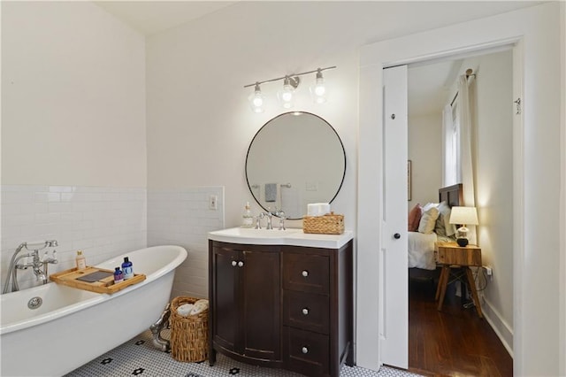 full bath with ensuite bath, a soaking tub, vanity, and tile walls