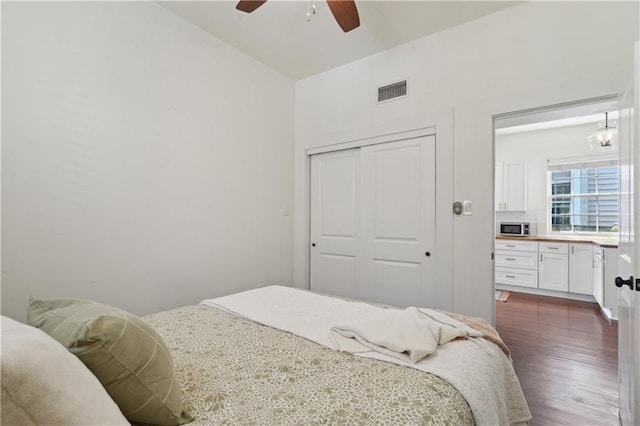 bedroom featuring dark wood finished floors, visible vents, a closet, and ceiling fan