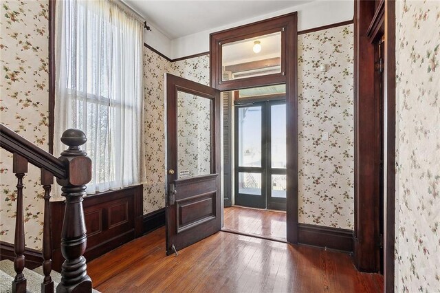 foyer entrance with french doors, stairway, and wallpapered walls