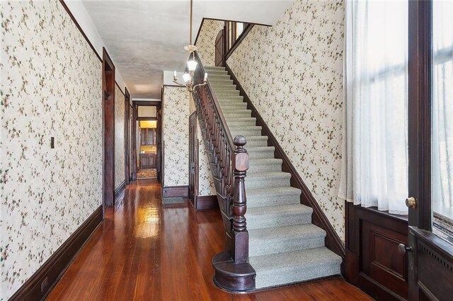 stairs featuring baseboards, wood finished floors, and wallpapered walls