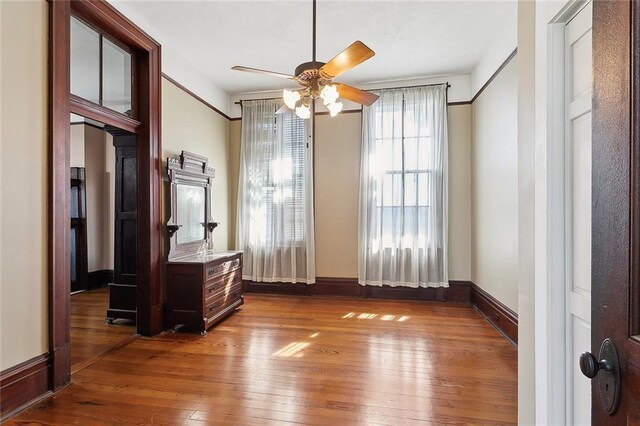 unfurnished room with dark wood finished floors, a ceiling fan, and baseboards