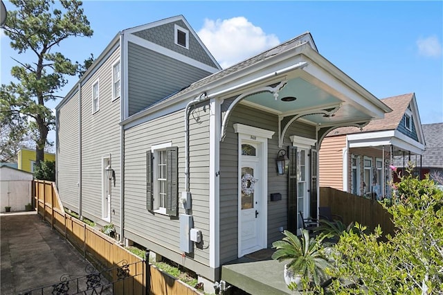 shotgun-style home with a storage unit, an outdoor structure, and fence