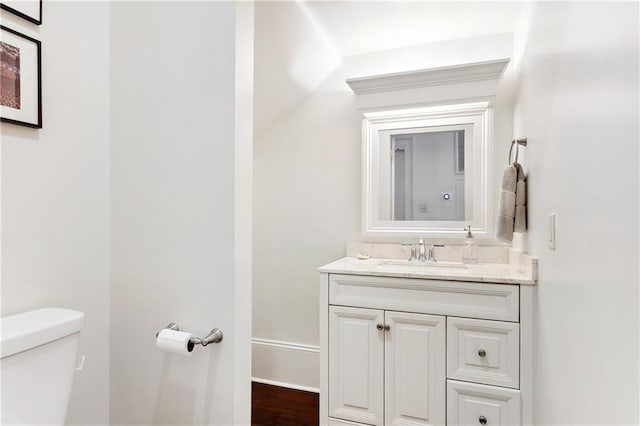 half bathroom featuring vanity, toilet, and baseboards