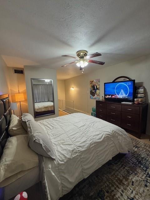 bedroom featuring ceiling fan, visible vents, and a textured ceiling