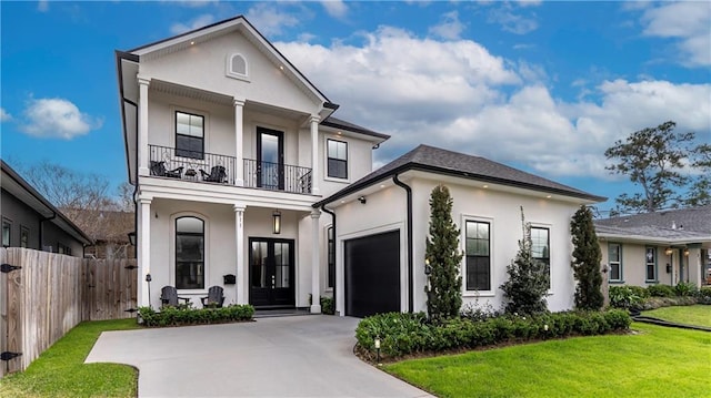 view of front facade with stucco siding, french doors, concrete driveway, and a balcony