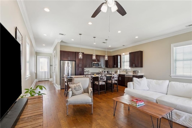 living room with visible vents, wood-type flooring, plenty of natural light, and crown molding