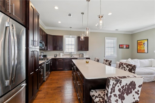 kitchen with visible vents, a kitchen island, open floor plan, stainless steel appliances, and a sink