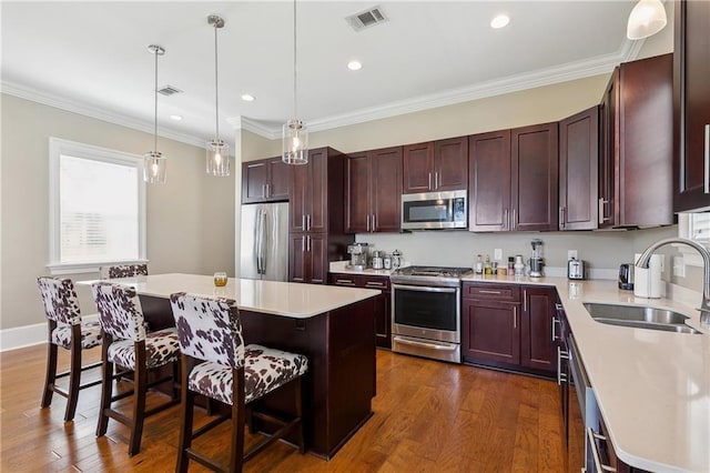 kitchen with visible vents, a kitchen island, a kitchen bar, appliances with stainless steel finishes, and a sink