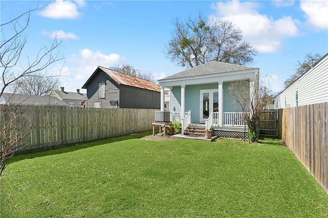 rear view of property with a yard, roof with shingles, covered porch, and a fenced backyard