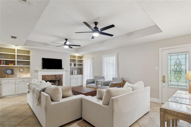 living room featuring visible vents, a tray ceiling, a textured ceiling, and ceiling fan
