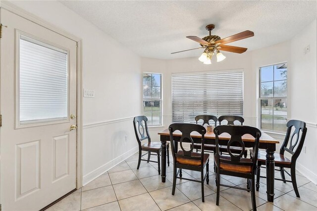 dining area with a textured ceiling, ceiling fan, baseboards, and light tile patterned floors