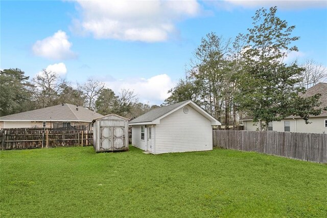 rear view of property featuring a yard, a fenced backyard, an outdoor structure, and a storage unit