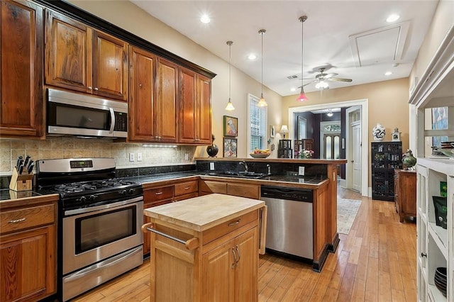 kitchen featuring a peninsula, appliances with stainless steel finishes, wood counters, decorative light fixtures, and tasteful backsplash