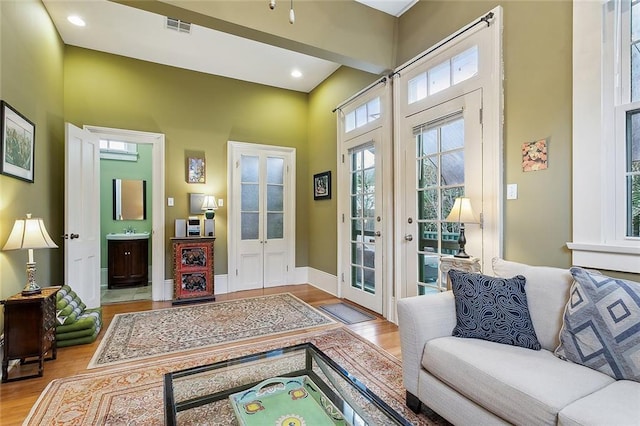 entryway with wood finished floors, visible vents, baseboards, a sink, and french doors