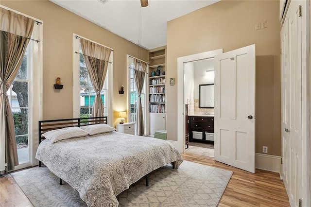 bedroom with access to exterior, baseboards, ensuite bathroom, and light wood-style floors