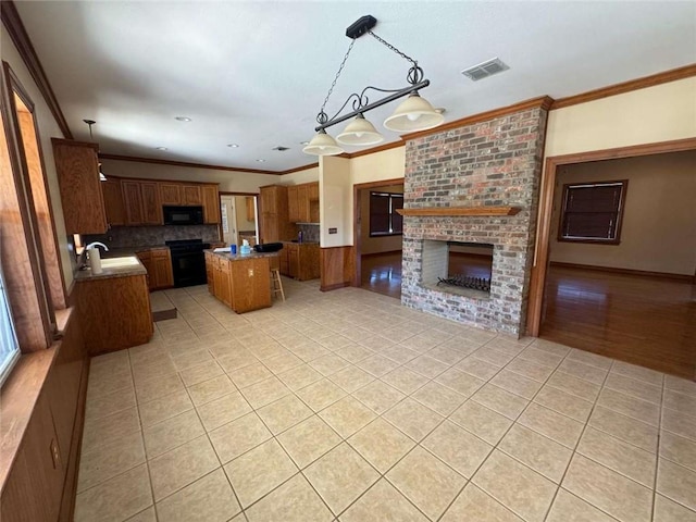 kitchen with visible vents, black appliances, ornamental molding, a fireplace, and light tile patterned floors