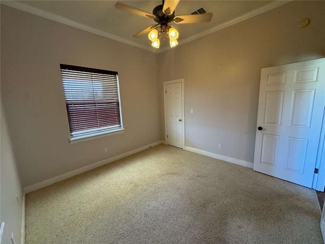 carpeted spare room featuring a ceiling fan, crown molding, baseboards, and visible vents