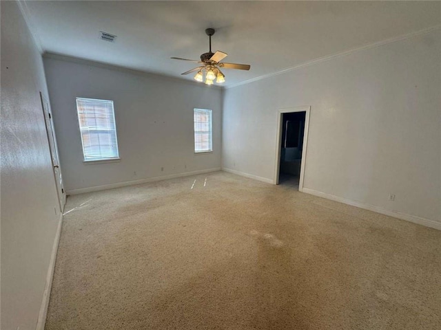 empty room with visible vents, light colored carpet, crown molding, and baseboards