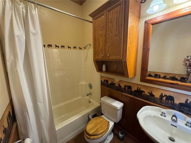 bathroom featuring a sink, shower / bath combo with shower curtain, and toilet