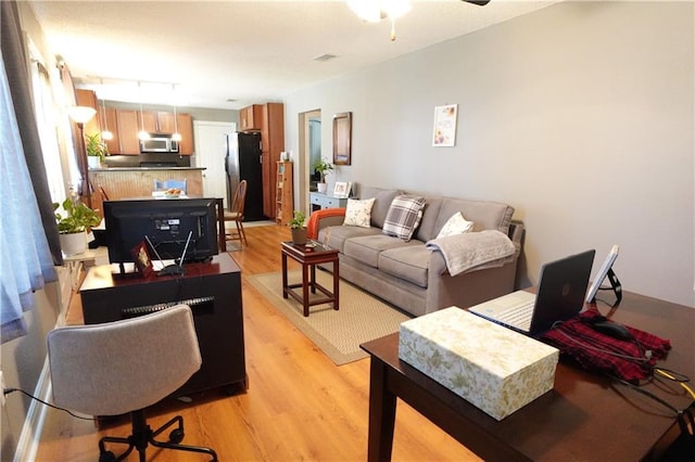 living area featuring visible vents, rail lighting, light wood-type flooring, and a ceiling fan