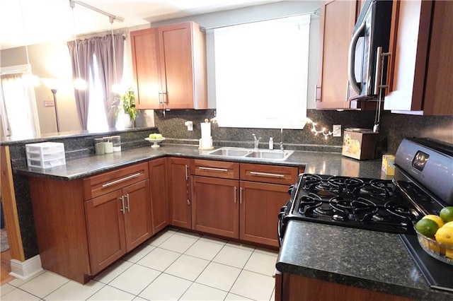 kitchen with a sink, stainless steel microwave, backsplash, gas stove, and a peninsula