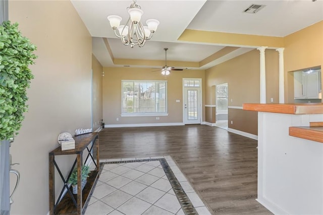 foyer entrance with baseboards, a raised ceiling, visible vents, and ceiling fan with notable chandelier