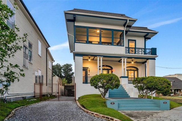 view of front of property with a balcony, a porch, a ceiling fan, and a gate