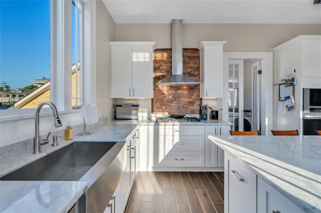 926 City Park Ave, New Orleans, LA 70119 - kitchen with wall chimney range hood, wood tiled floor, light stone counters, white cabinets, and a sink