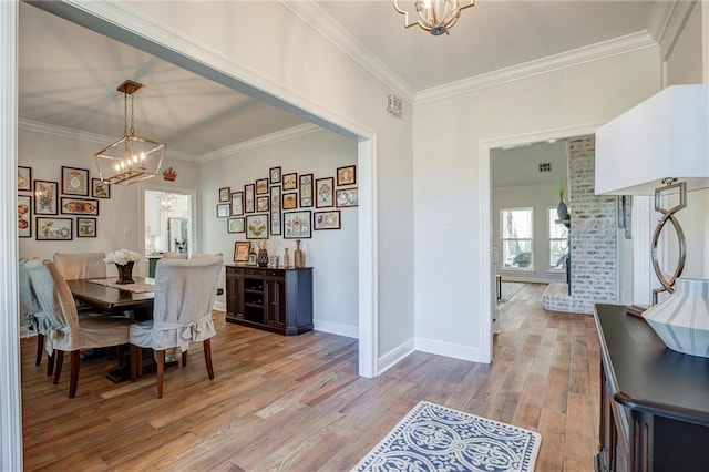 dining space featuring light wood-style flooring, a chandelier, and ornamental molding