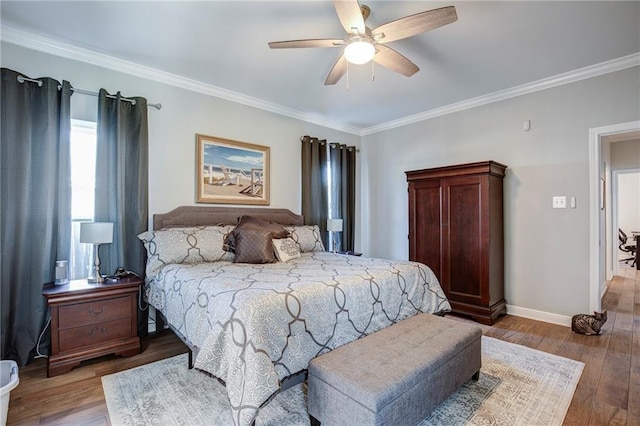 bedroom with a ceiling fan, crown molding, wood finished floors, and baseboards