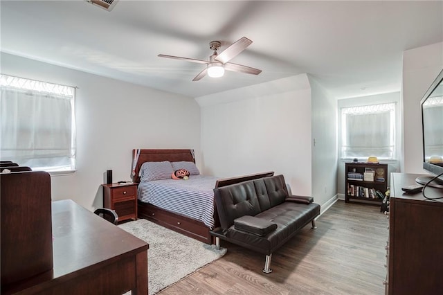 bedroom with a ceiling fan, wood finished floors, baseboards, visible vents, and lofted ceiling