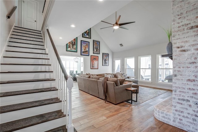 living room with high vaulted ceiling, light wood-style flooring, recessed lighting, stairway, and ceiling fan