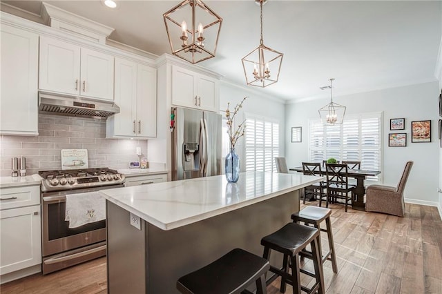 kitchen with under cabinet range hood, stainless steel appliances, crown molding, and light countertops