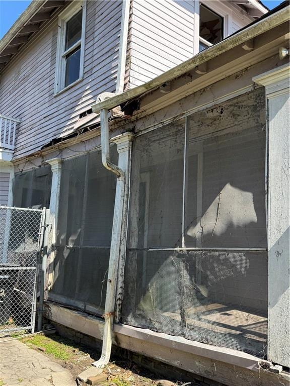 view of side of home with fence and a sunroom