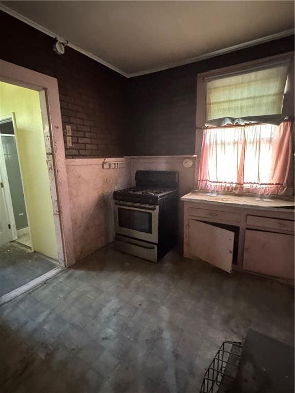 kitchen featuring stainless steel gas range oven, tile patterned floors, and crown molding