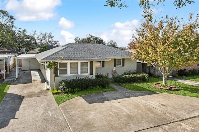 view of front of property with a front lawn, driveway, fence, roof with shingles, and an attached carport