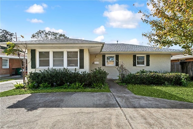 single story home with fence, brick siding, and a shingled roof