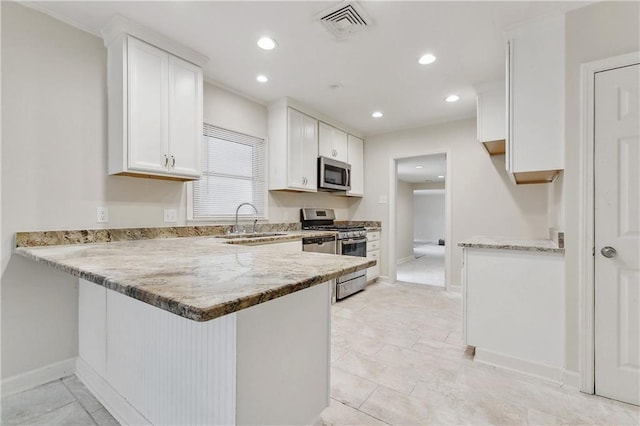 kitchen with visible vents, a peninsula, a sink, white cabinets, and appliances with stainless steel finishes