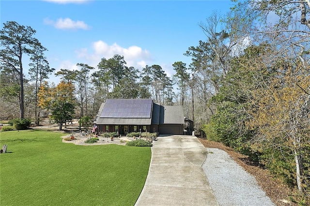 view of front facade with solar panels, concrete driveway, and a front lawn