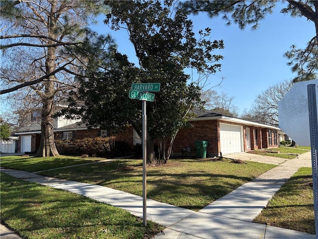 view of front facade with brick siding, an attached garage, driveway, and a front lawn