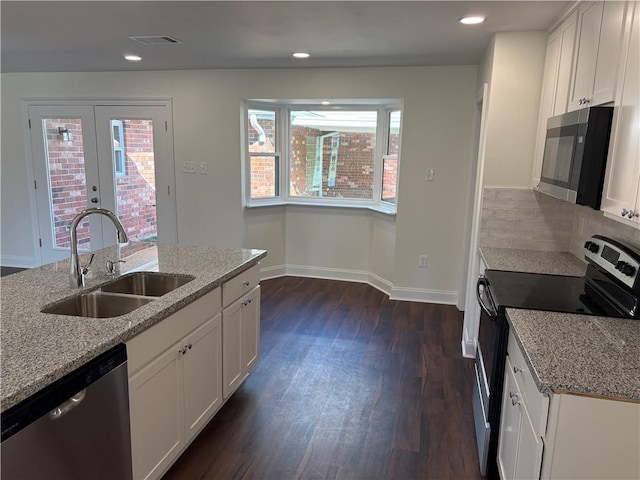 kitchen with light stone countertops, visible vents, a sink, stainless steel appliances, and dark wood-type flooring