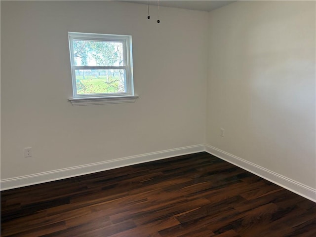 spare room with dark wood finished floors and baseboards