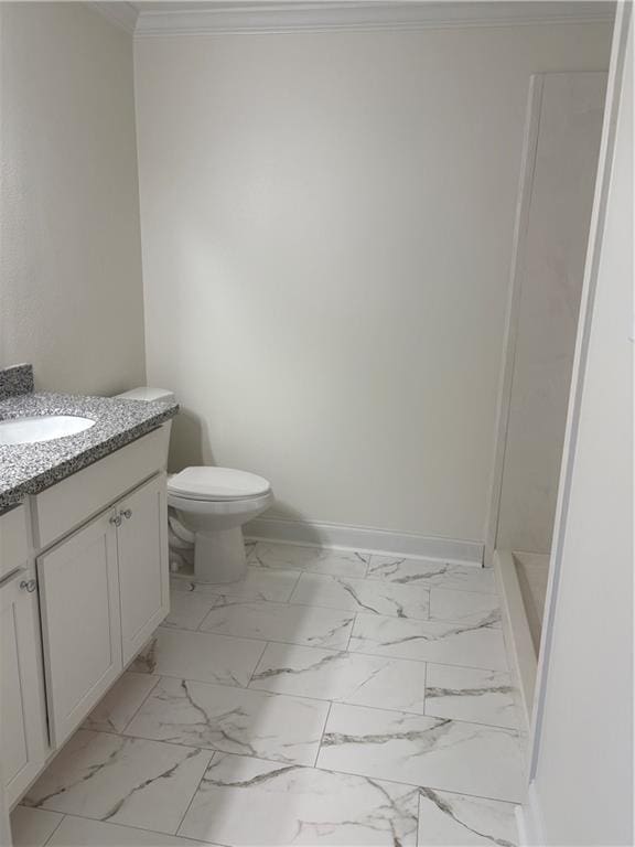 bathroom with vanity, baseboards, ornamental molding, toilet, and marble finish floor