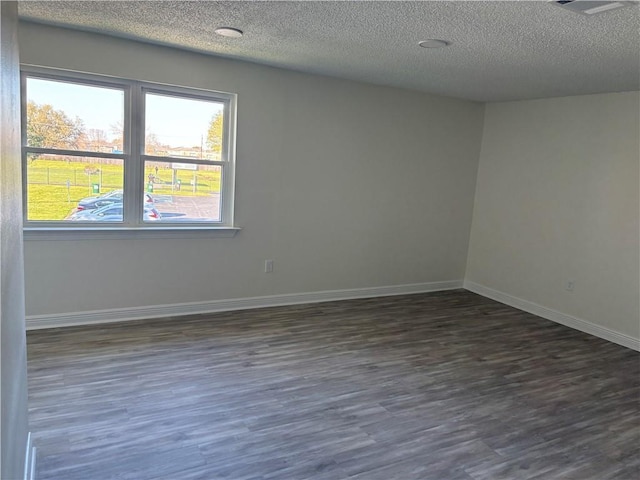 spare room with baseboards, a textured ceiling, and dark wood-style floors